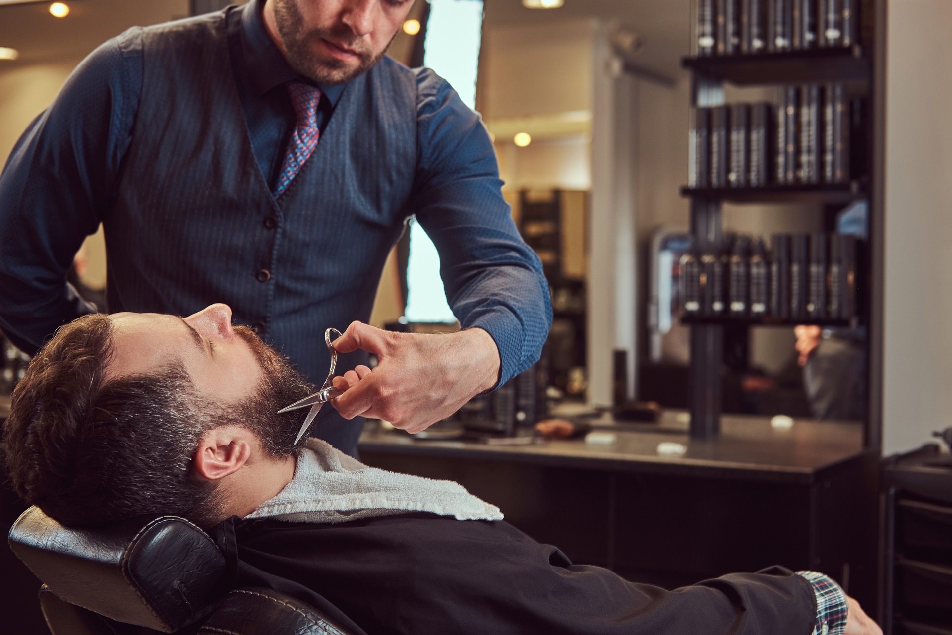 Barbier Prestige Barbers réalisant une taille de barbe aux ciseaux à Fréjus